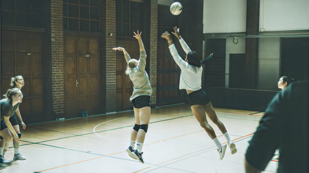 Young female volleyball players in action during a match. Focus on the players jumping to spike the ball.の写真素材