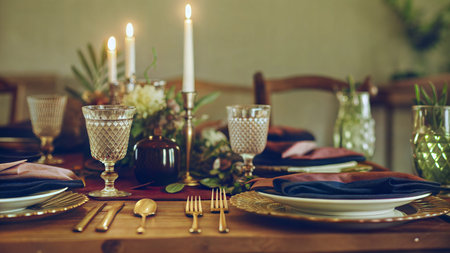 Close-up of a beautifully decorated table setting with candles, glasses, plates, and napkins. ...