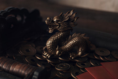 A bronze dragon statue sits atop a pile of antique Chinese coins, suggesting wealth and prosperity. Dark and moody lighting.の写真素材