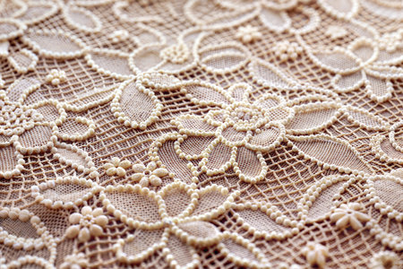 Close-up of beige lace fabric adorned with delicate pearl beads, creating intricate floral patterns.の写真素材