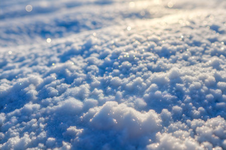 Close-up of snow glistening in the sunlight, showing texture and bokeh effect.