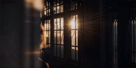 Golden sunlight streams through a vintage window pane, illuminating a dark room. A person is seen in...