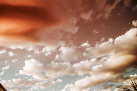 Stunning sunset with fluffy clouds painted in warm orange and soft beige tones.
