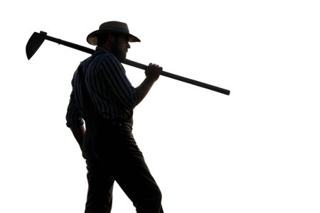 Silhouette of a farmer carrying a hoe against a black background.  Strong image for themes of...