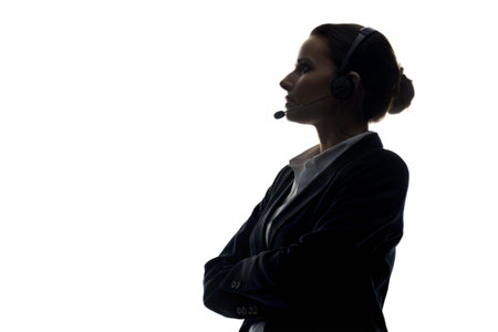 Silhouette of a businesswoman wearing a headset, arms crossed, against a black background.