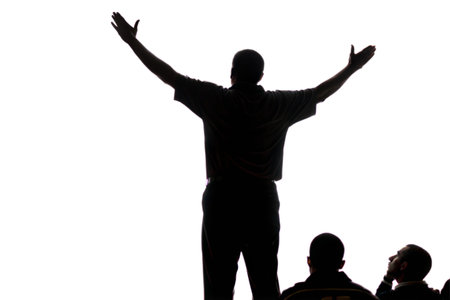 Backlit silhouette of a man giving a presentation, with two people in the audience looking up at him.の写真素材