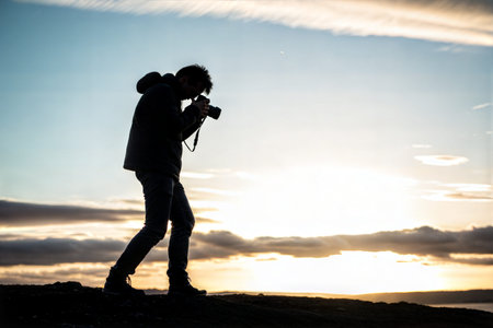Silhouette of a photographer taking pictures during a beautiful sunset. The image evokes a sense of peace and serenity.の写真素材