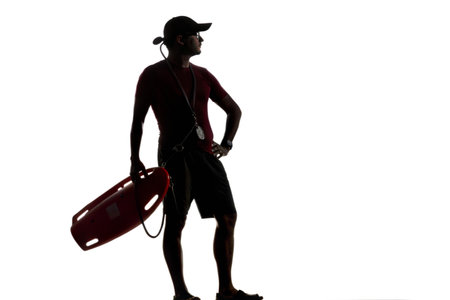 Silhouette of a lifeguard standing with a rescue tube, ready for action against a black background.