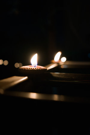 A close-up shot of lit candles in the dark, creating a warm and serene atmosphere.の写真素材