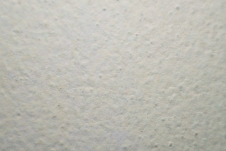 Abstract background featuring a light, off-white textured surface with subtle bumps and variations....