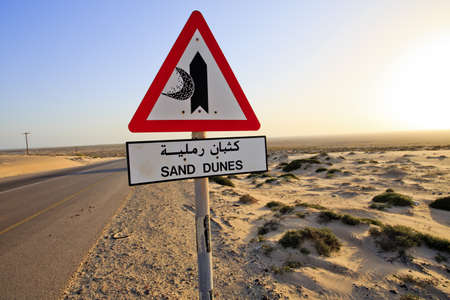 Sand Dunes sign and road in the middle of the desert in Oman on Route 35 の写真素材