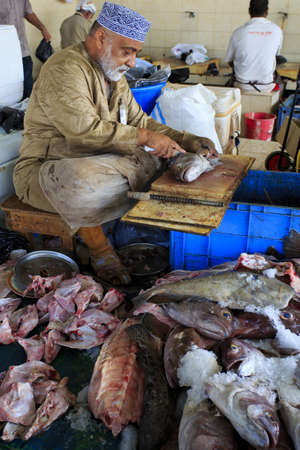 Muscat, Oman - March 26, 2013  Unidentified Oman fishmonger, in Mutrah fish market prepares fish for sale のeditorial素材