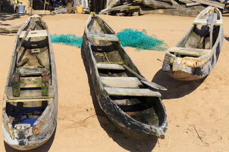 Three old dugout canoes on the beach with nets in Axim, Ghanaの写真素材