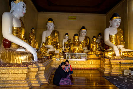 Yangon, Myanmar, 9th November 2015: The Shwedagon pagoda in Yangon embraces people, not just to worship, here two young girls are pictured playing with their smartphones. Myanmar has changed significantly in the last few years since sanctions have been liのeditorial素材