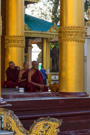Yangon, Myanmar, 9th November 2015: Three monks pray in a line at the Shwedagon pagoda in Yangonのeditorial素材