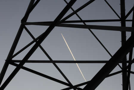 tower high-voltage lines and the trace of an airplane against the blue skyの写真素材