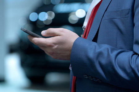 a man in a blue suit is holding a mobile phone in his hand