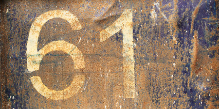 white number sixty-one on a rusty coarse, peeling metal surface