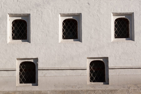 strong stone wall of the monastery or fortress with small windows with bars