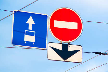 three traffic signs hang on wires above the road against a blue sky, prescribing traffic rulesの写真素材