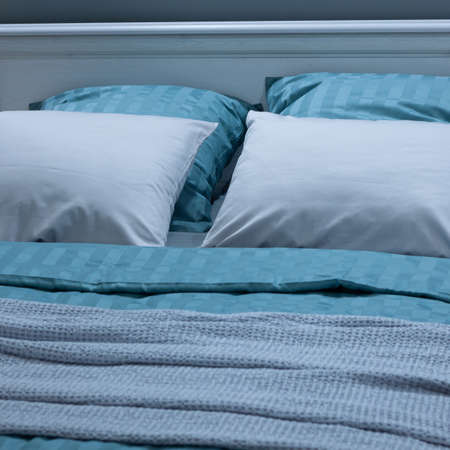 cozy double bed with soft beautiful pillows and a bedspread for relaxing and sleeping at homeの写真素材