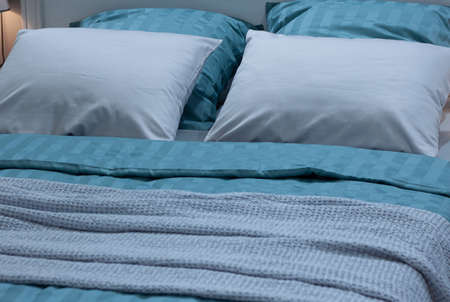 cozy double bed with soft beautiful pillows and a bedspread for relaxing and sleeping at homeの写真素材