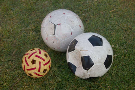 dirty soccer football and sepak takraw on green grass fieldの写真素材