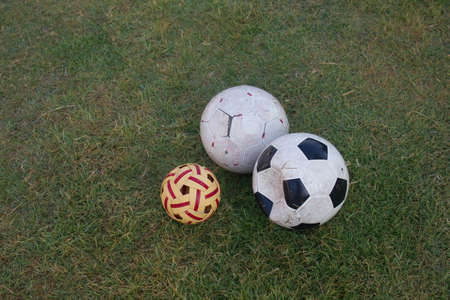 dirty soccer football and sepak takraw on green grass fieldの写真素材