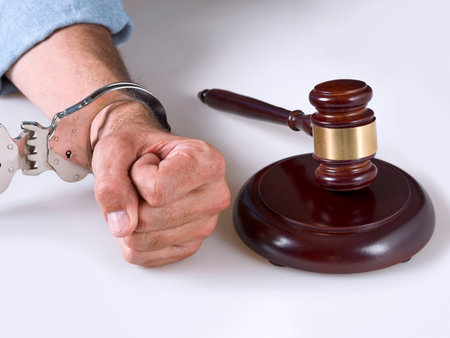 A hand handcuffed next to a gavel