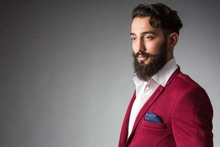 Elegant Man with Beard and Mustache wearing stylish suites in front of a gray studio backgroundの写真素材