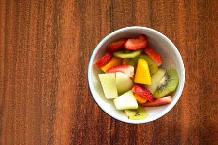 Bowl with tropical fruits on a wood tableの写真素材