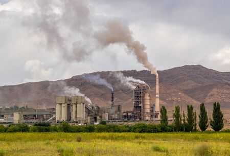 Hazardous and toxic smog created by power plant emissions with trees in foregroundの写真素材