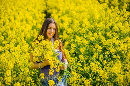 country girl in a scarf in a raps field in summerの写真素材