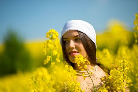 country girl in a scarf in a raps field in summerの写真素材