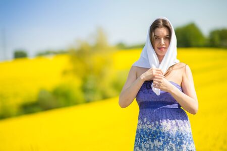 country girl in a scarf in a raps field in summerの写真素材