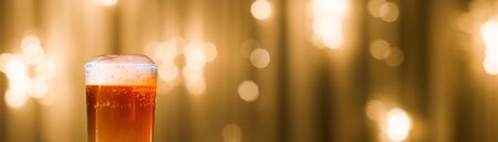 light beer in a figured glass on a black table on a blurred backgroundの写真素材