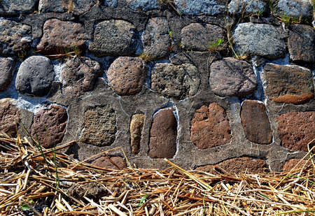 background of the stone wall of large boulders and dry reedの写真素材