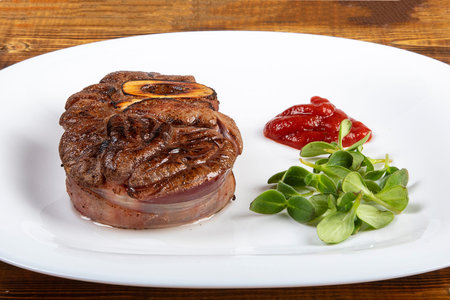 Meat with herbs and ketchup on a white plate. Board.の写真素材