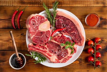 Pieces of beef of various kinds on a white plate. Pepper, cherry tomatoes, rosemary, arugula, sauce. Board. Topの写真素材