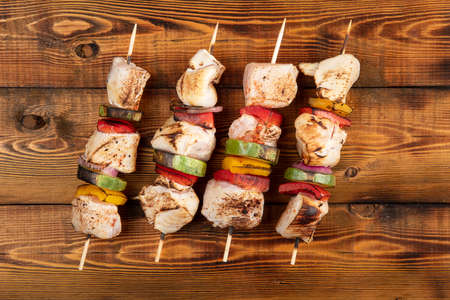 Chicken shish kebab on wooden skewers lies on the board.の写真素材