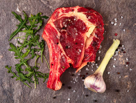 Raw meat on a gray background. Garlic, arugula. Top.の写真素材