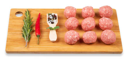 Raw meat balls on a chopping board. Rosemary, chili pepper, spices. White background.の写真素材