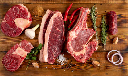 Pieces of raw meat on a wooden table. Pepper, garlic, spices. Top view.の写真素材