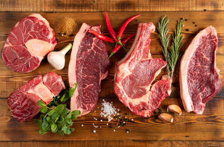 Pieces of raw meat on a wooden table. Chili pepper, garlic, rosemary, spices.Top view.の写真素材