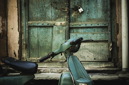 an old scooter in front of a a dilapidated door with lock in Mathura, indiaの写真素材