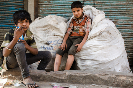 NEW DELHI, INDIA - 23 APRIL 2016 : portrait of two Indian boys sitting on garbage bagsのeditorial素材