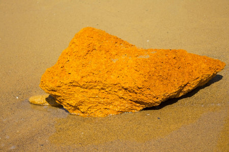 Lone yellow stone on the sea shore