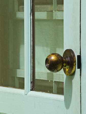A used brooze doorknob on light blue doorの写真素材
