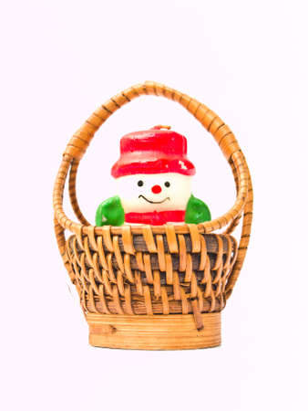 A christmas snow doll candle and a  yellow wicker basket isolated on white backgroundの写真素材