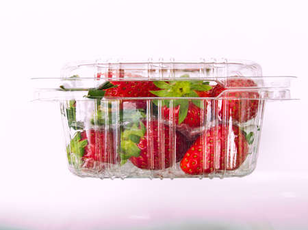Fresh Strawberry piled in clear plastic box Isolated on white backgroundの写真素材